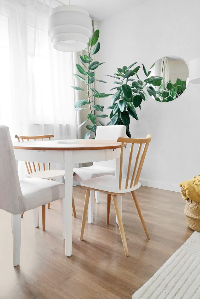 Skandi-Boho-Vintage Wohnzimmer mit grauem Sofa, hellem Holz, orangefarbenem Akzentkissen und hellen Wänden.